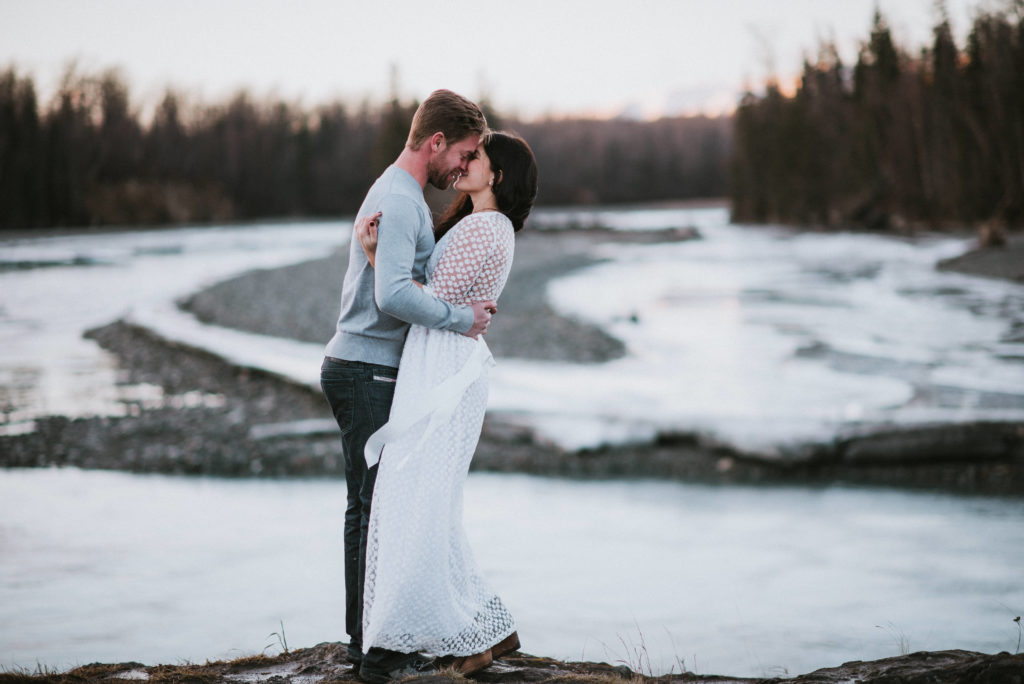 A couple kissing standing by a river