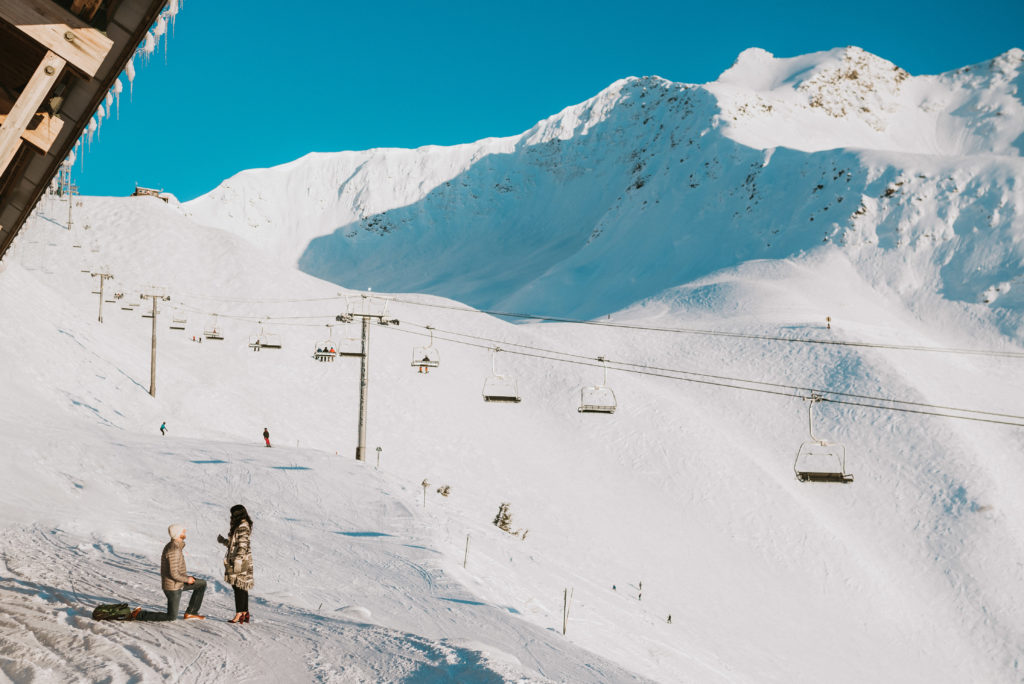 A man proposing to his girlfriend on the top of snow mountainside at alyeska resort