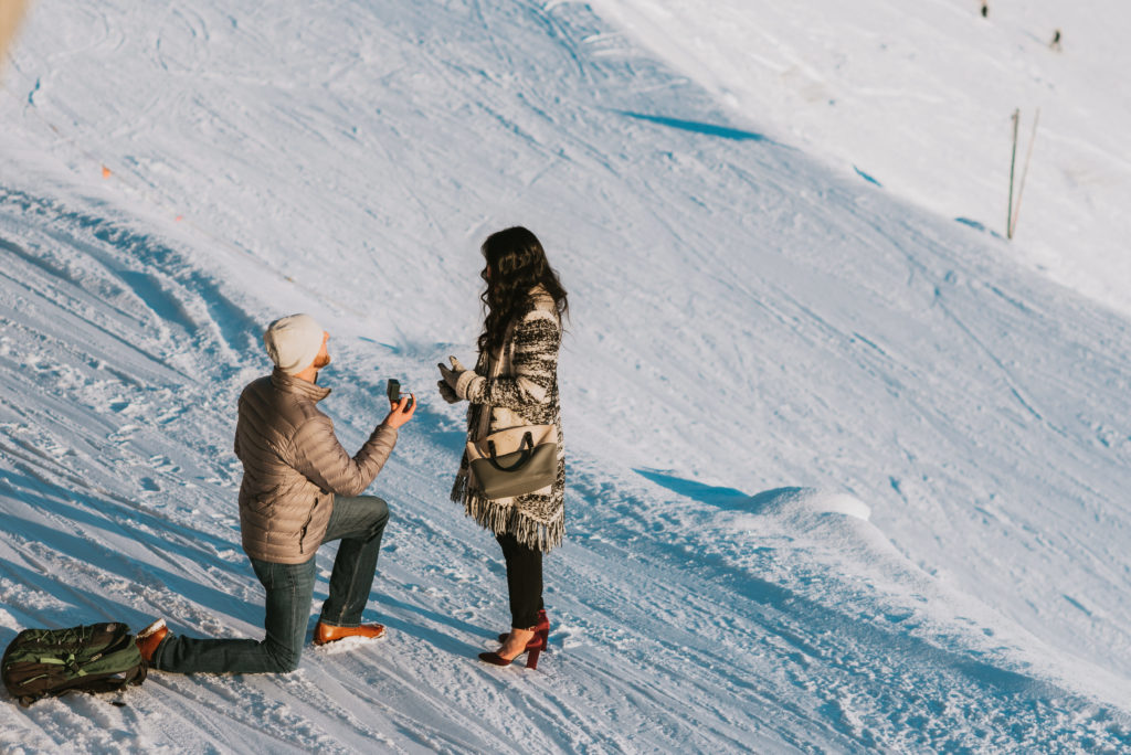 A man proposing to his girlfriend on the top of snow mountainside at alyeska resort