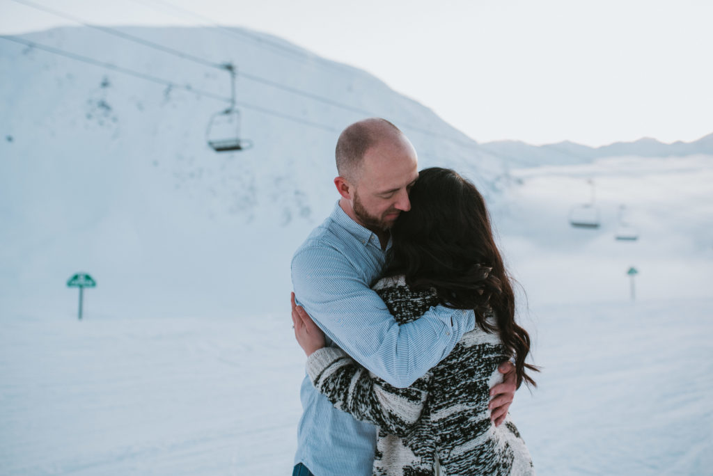 Couple hugging in the snowy mountains after surprise proposal