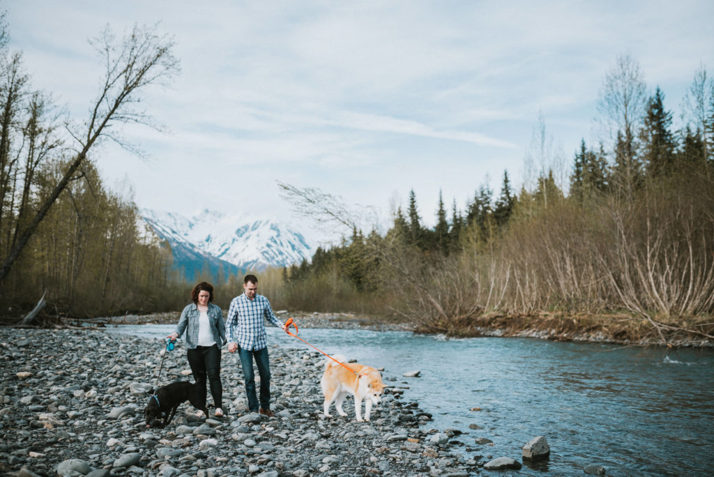 couple walking dog on riverbed during gridwood engagement session