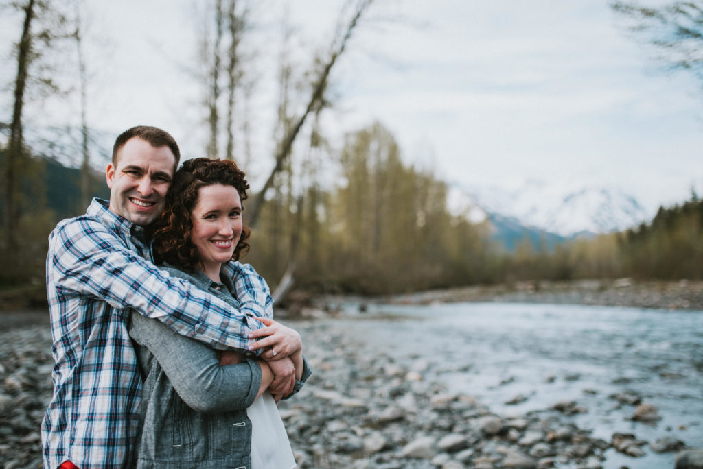 couple hugging and laughing on girdwood riverbed