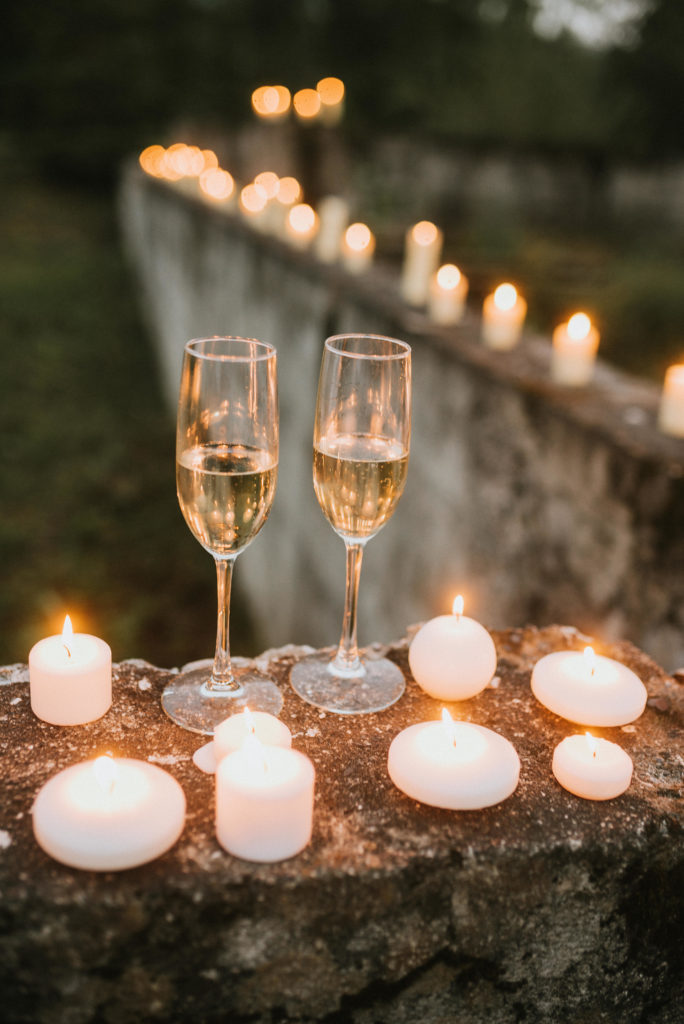 Candlelit champagne glasses against concrete ruins