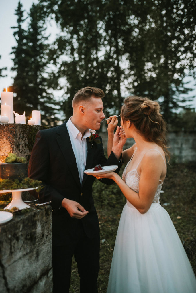 Wedding couple cutting black cake with gold splatter and moss