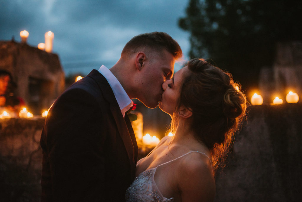 Bride and groom kissing in candlelit setting