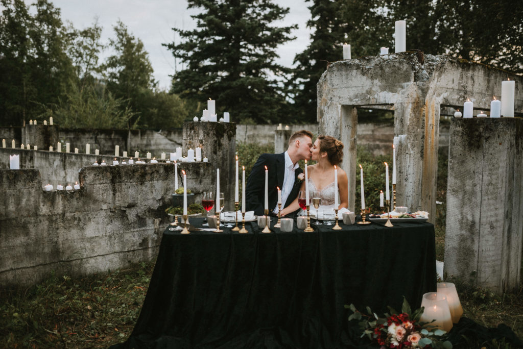 Couple sitting at beautifully done up sweetheart table with candles