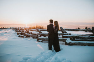 Couple staring out over sunset on snowy mountain together