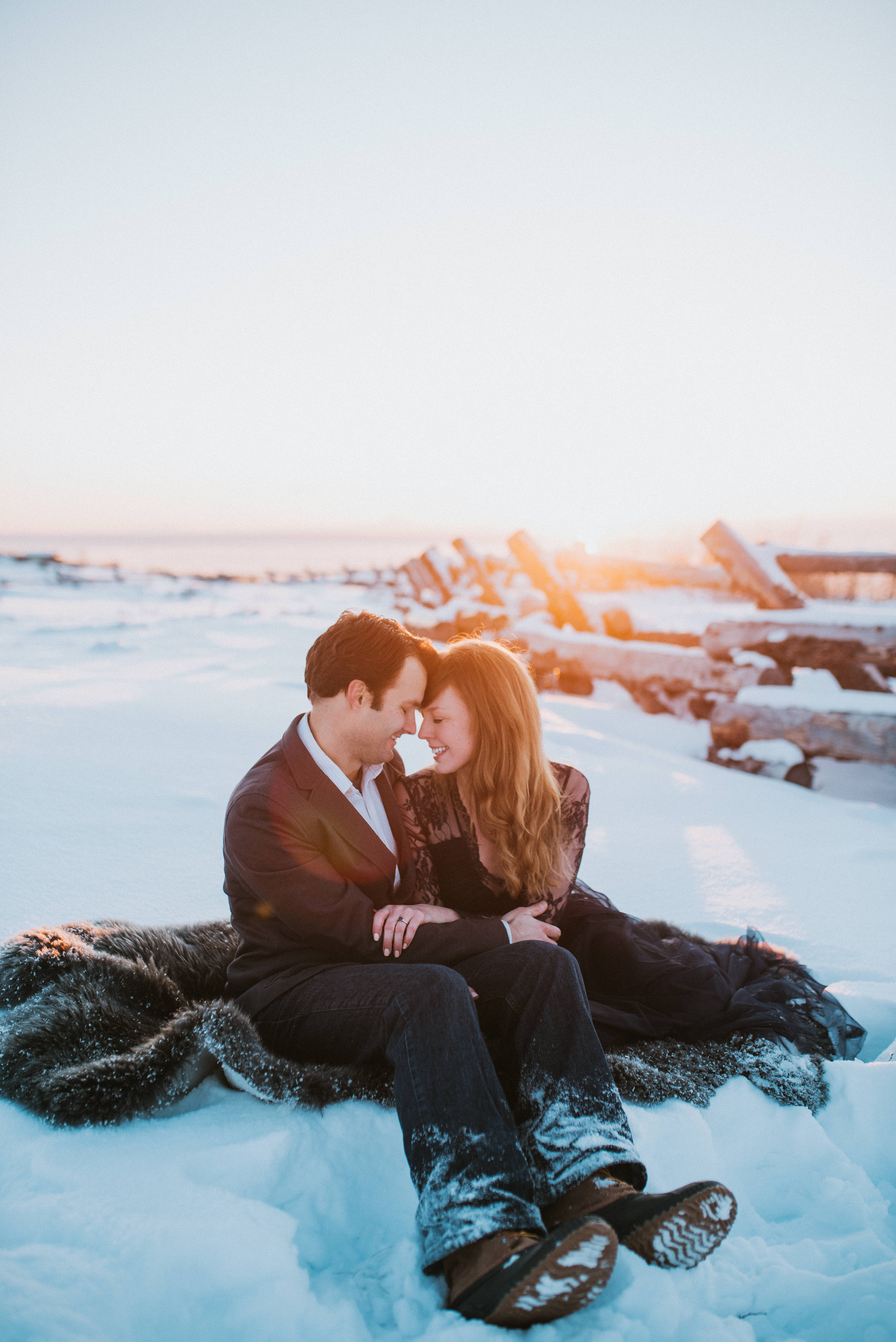 Couple sitting on fur rug snuggling with sunset light