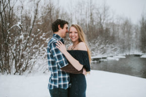 Couple snuggling close smiling in snow