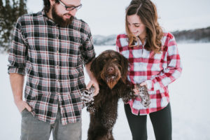 couple holding hands with their labradoodle dog for engagement photos