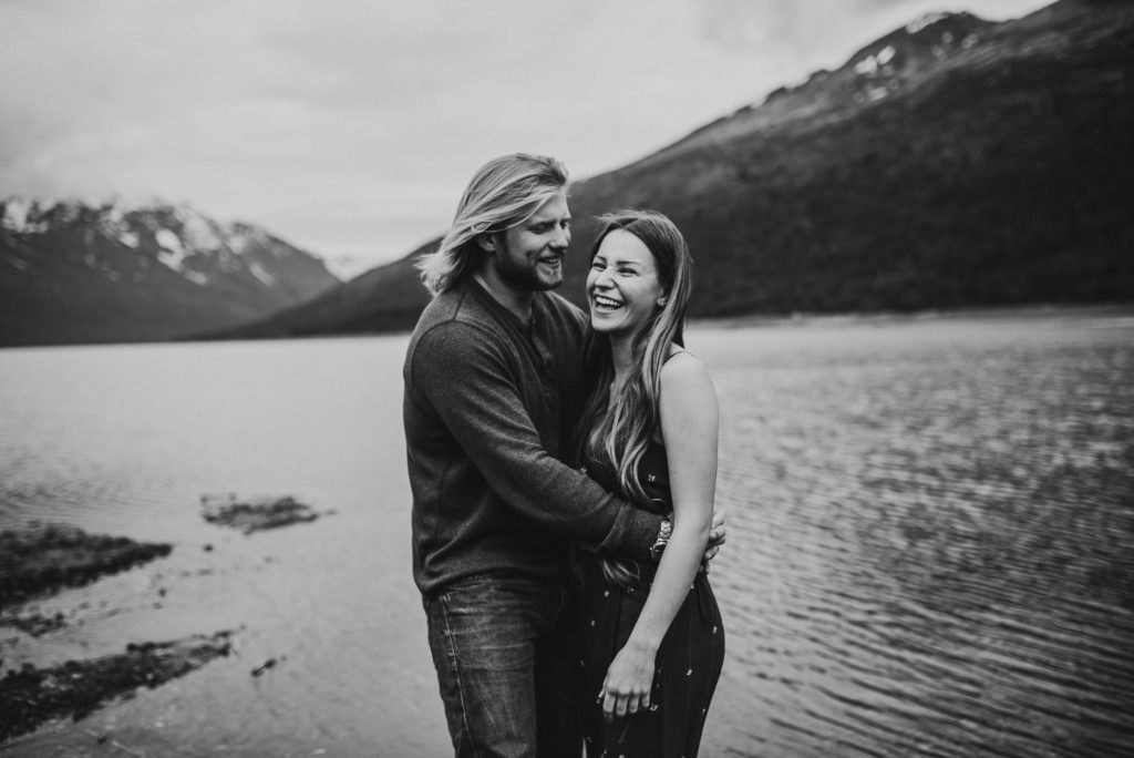 Black and white photo of couple hugging on lake shore
