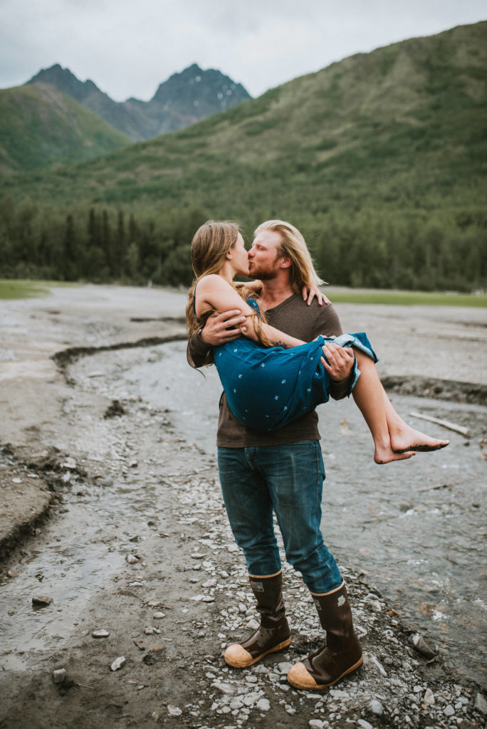 Guy carrying girlfriend on the lake shore while kissing