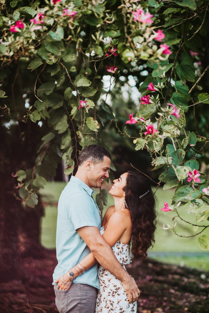 Couple standing under pink flower tree laughing