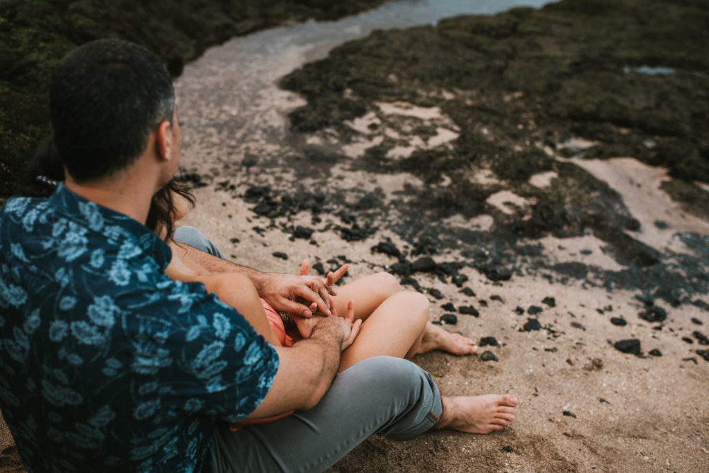 Couple is sitting on the beach, fingers interlaced