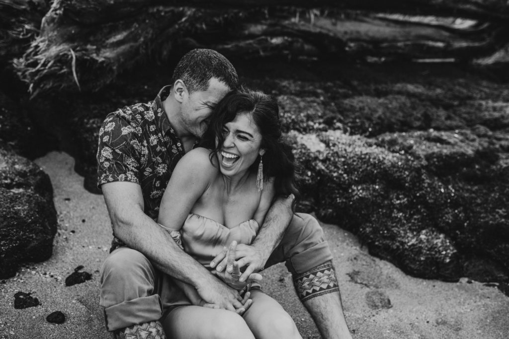 Couple laughing and snuggling on a sandy beach
