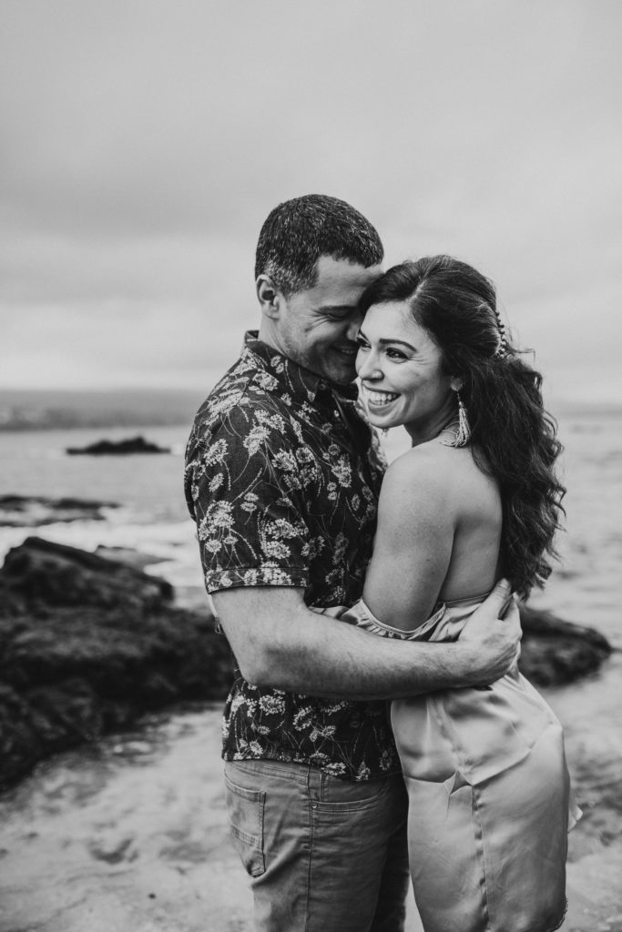 A couple hugging on a beach laughing and smiling