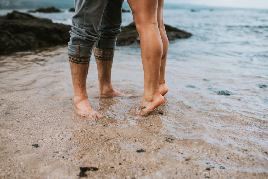 A couple standing in the water, detail shot of their feet and she is on her tip toes
