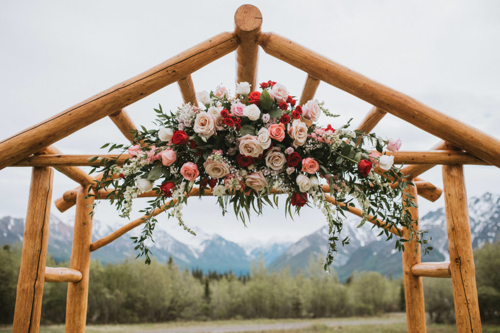 wedding arch with pink, maroon and white flowers and greenery