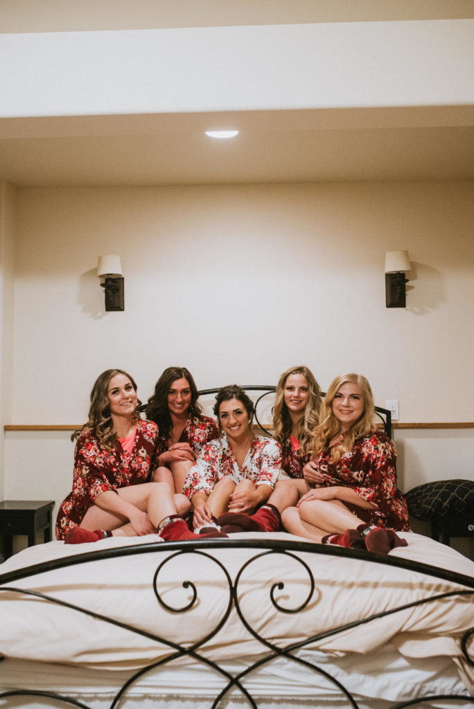bride and bridesmaids sitting on bed pose