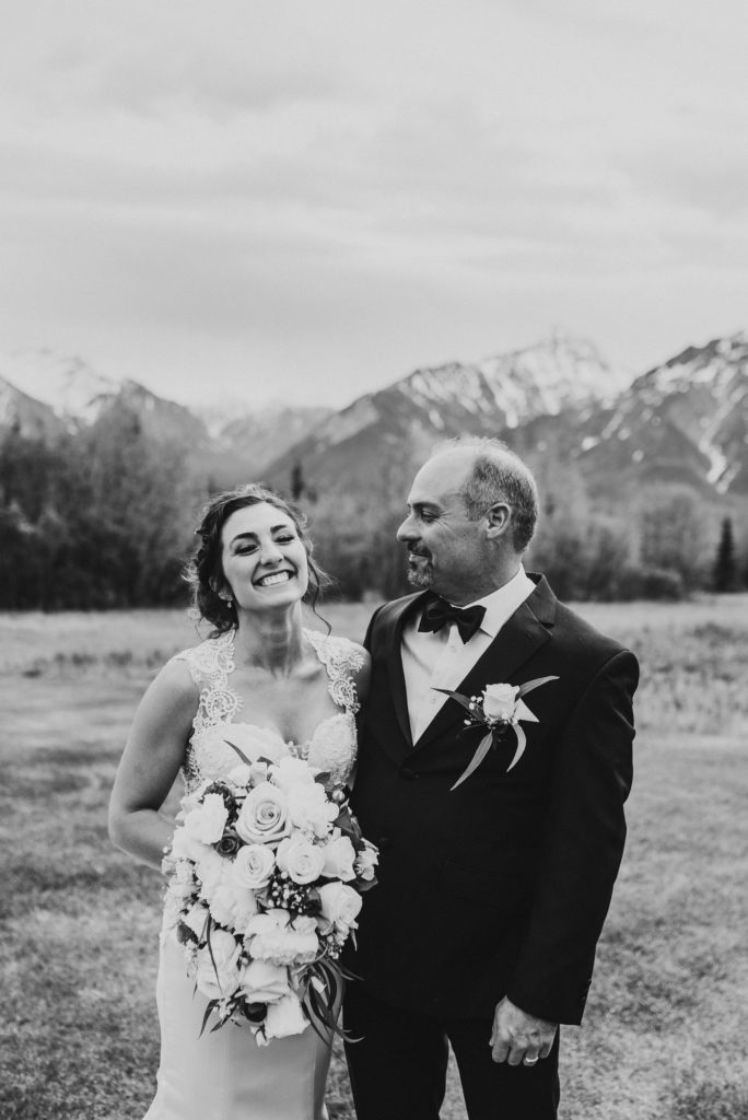 Bride and father laughing with a mountain backdrop