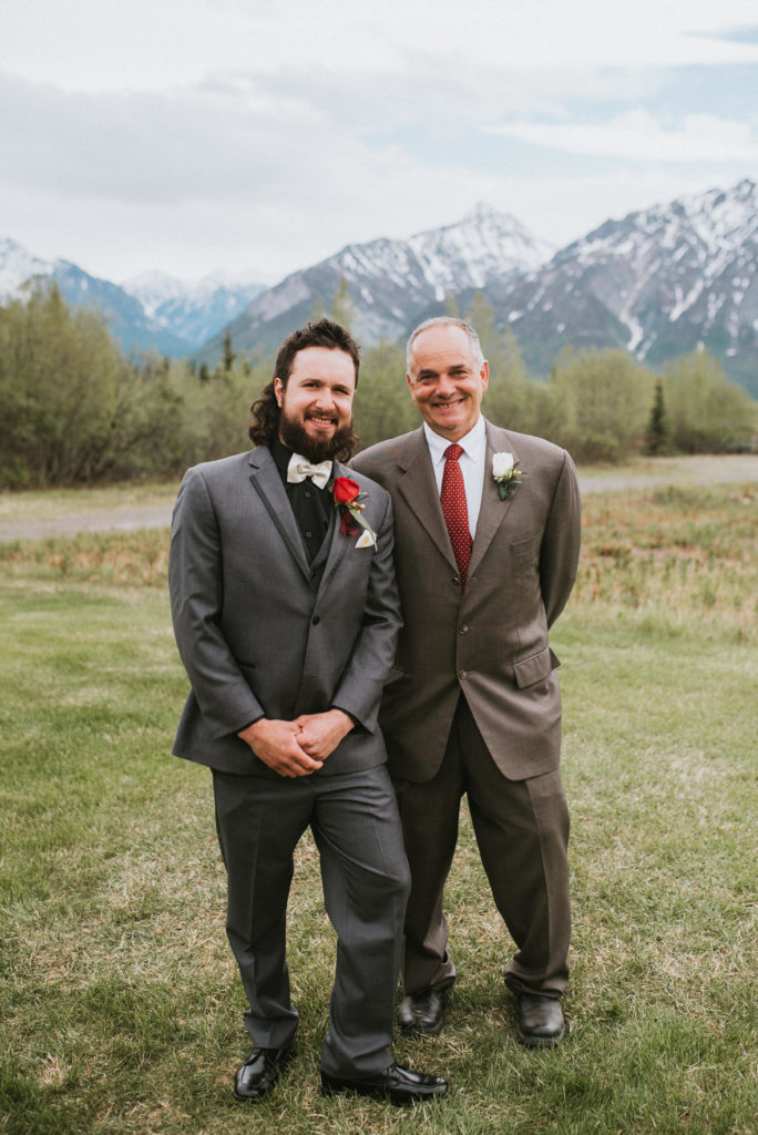 Groom and father smiling for portrait against the mountains