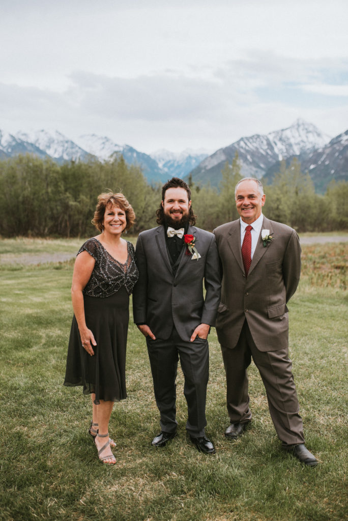 Groom with both parents against mountain backdrop