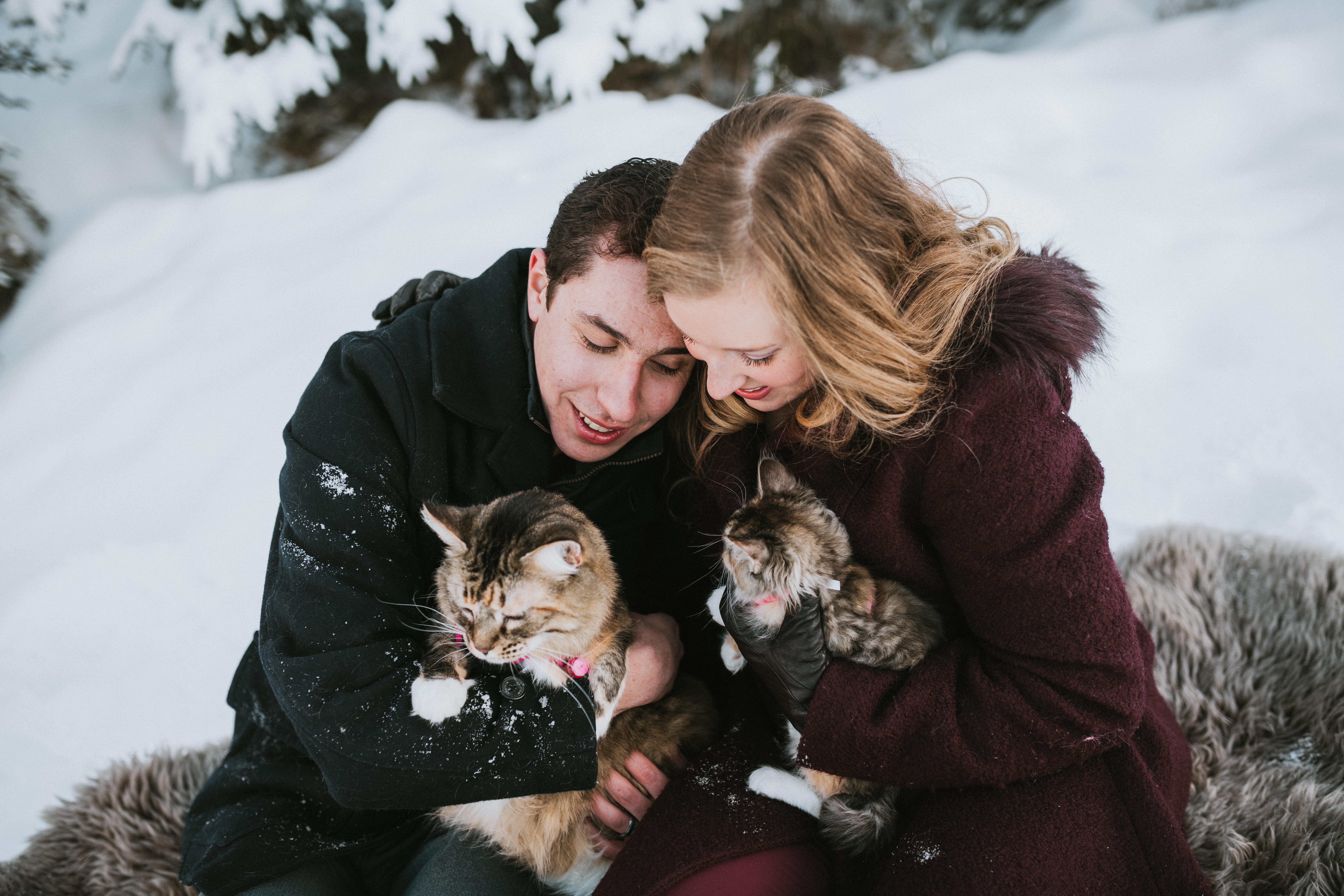 Couple smiling at camera with their two cats