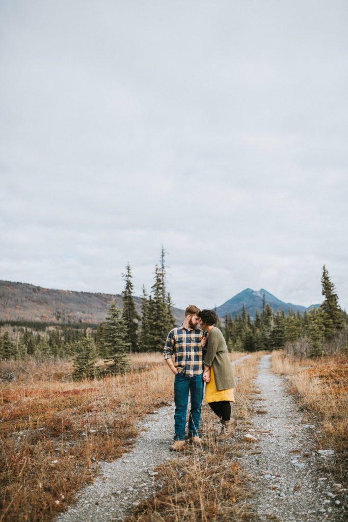 Couple snuggling in fall setting in alaska during their engagement session