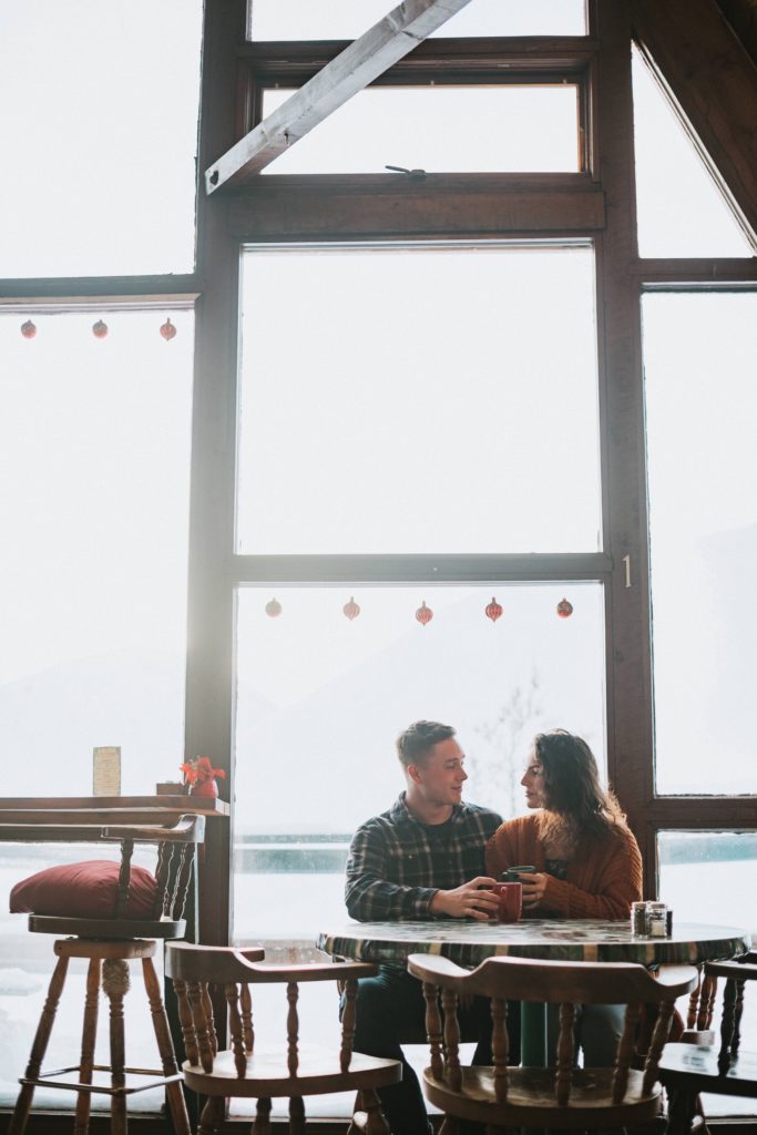 Couple snuggling up and drinking coffee during their engagement session in Hatcher Pass Lodge