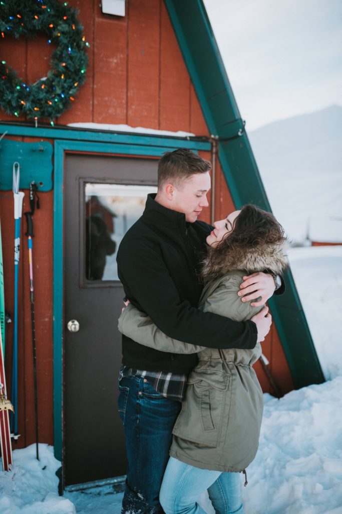 Couple standing in front of hatcher pass red cabin for their engagement session