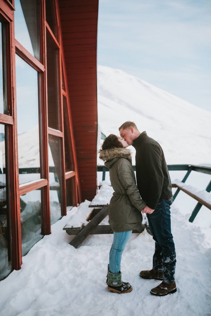 Couple kissing in front of iconic Hatcher Pass Lodge in Alaska