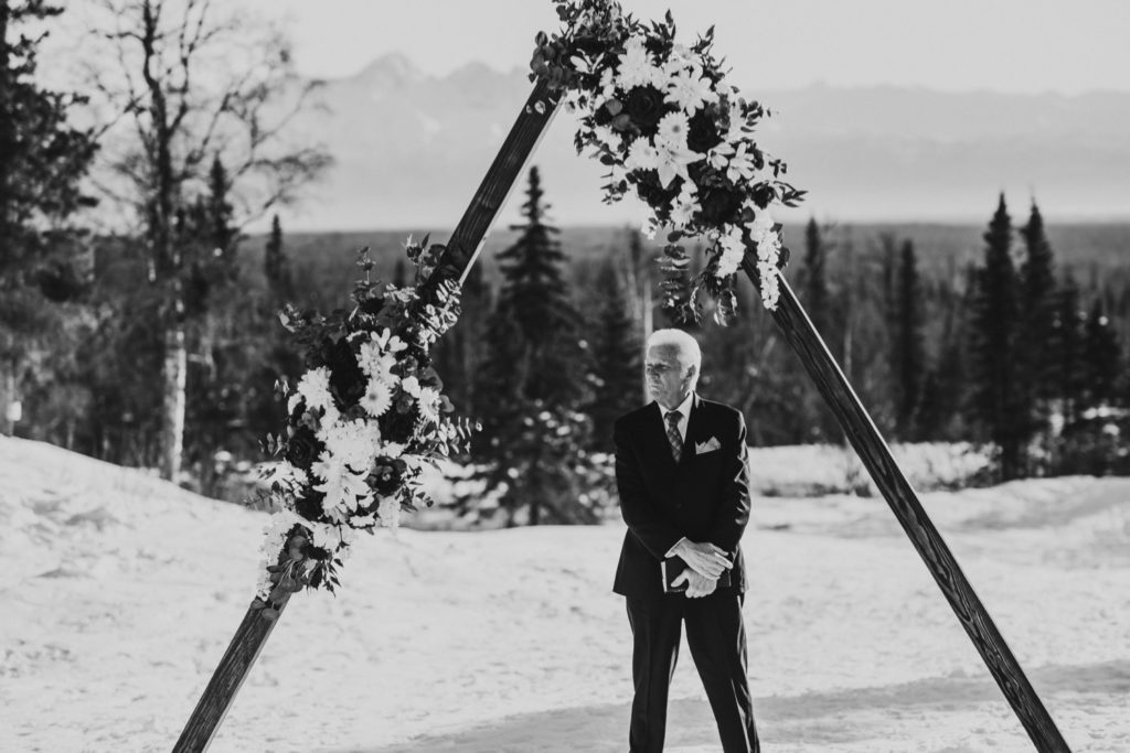 Black and white photo of grandfather officiating an Alaska winter wedding