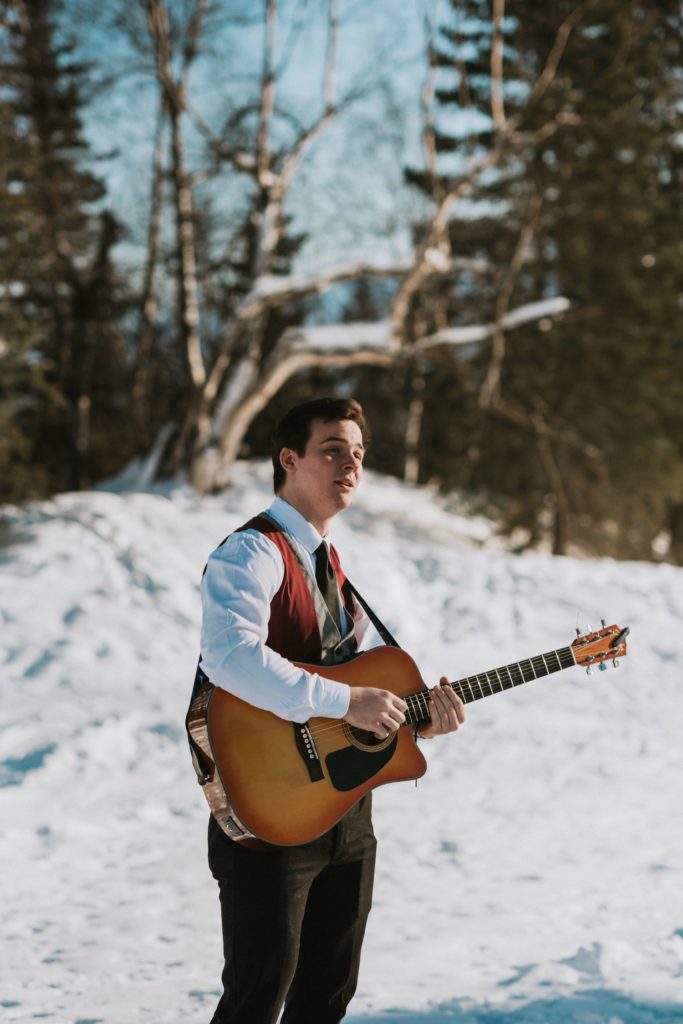 A man playing the guitar at an Alaska winter wedding