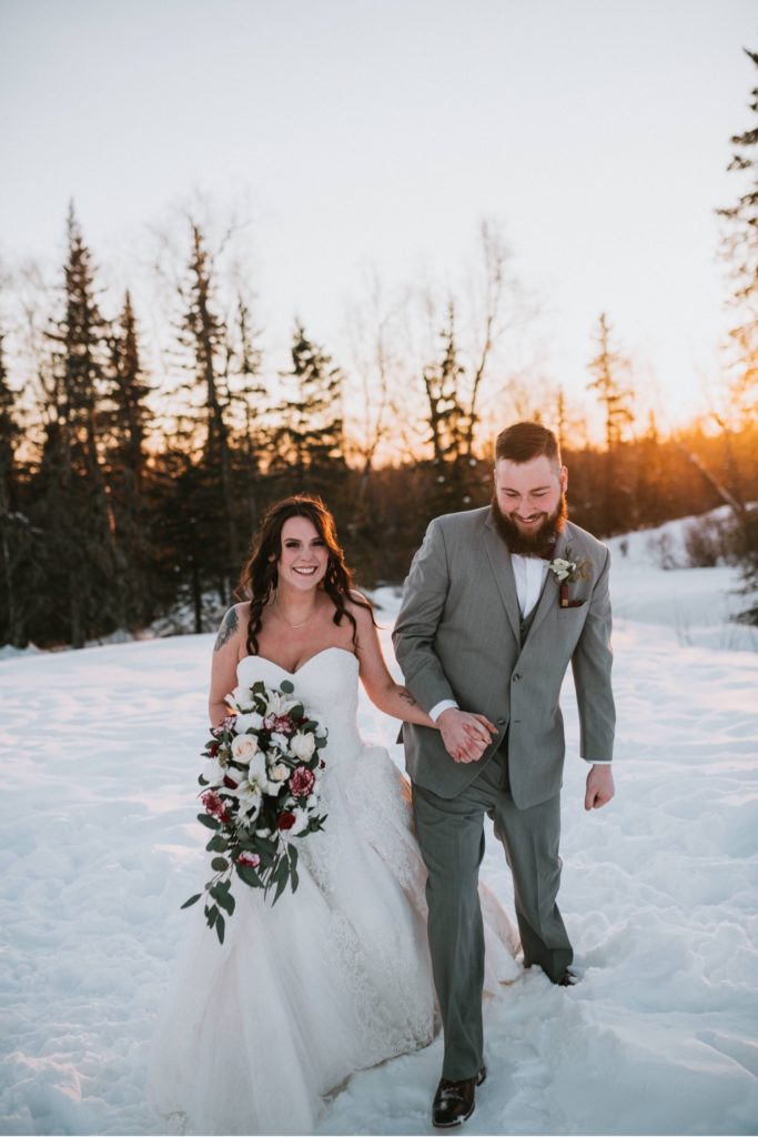 Bride and groom walking in the snow and sunset