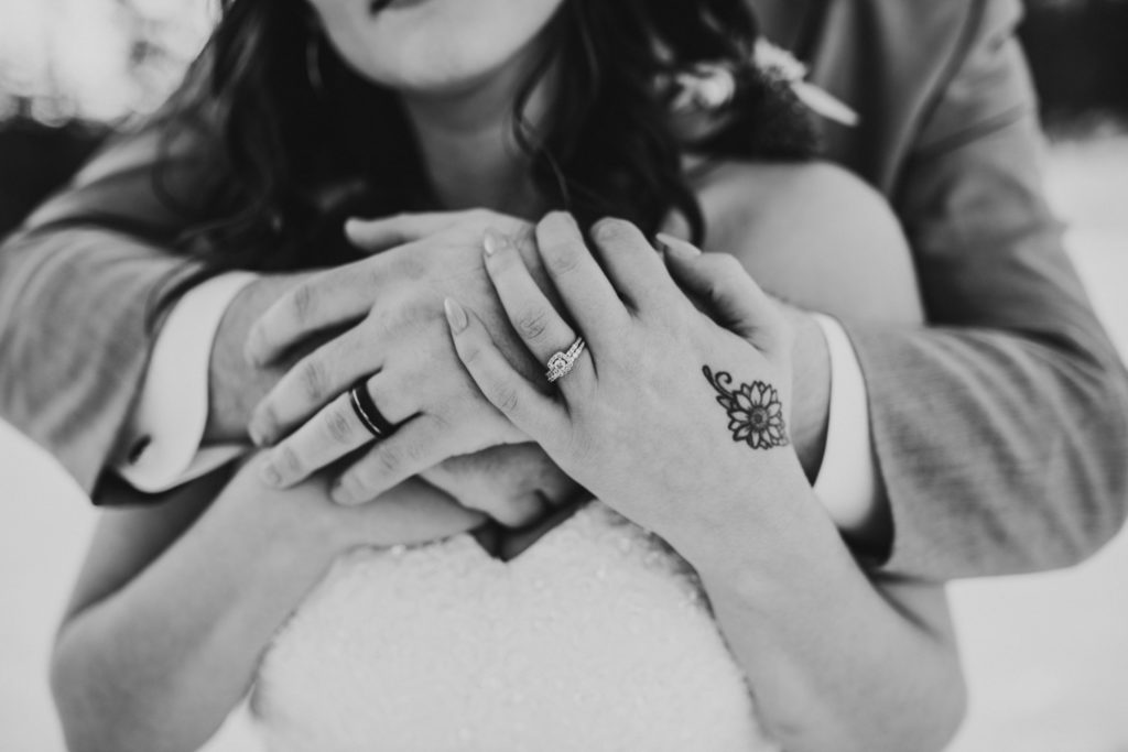 Detail photo of the bride and grooms rings while hugging