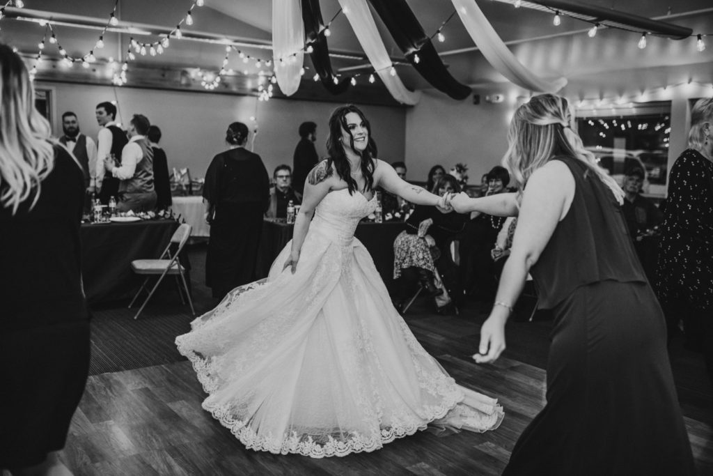 Bride twirling at wedding while dancing with sister in law