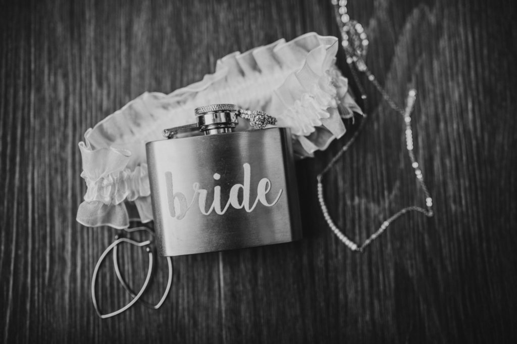 Black and white photo of brides details with her flask and jewelry