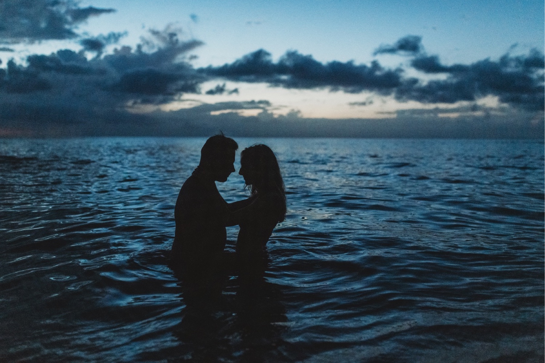 Couple snuggling in the water after sunset