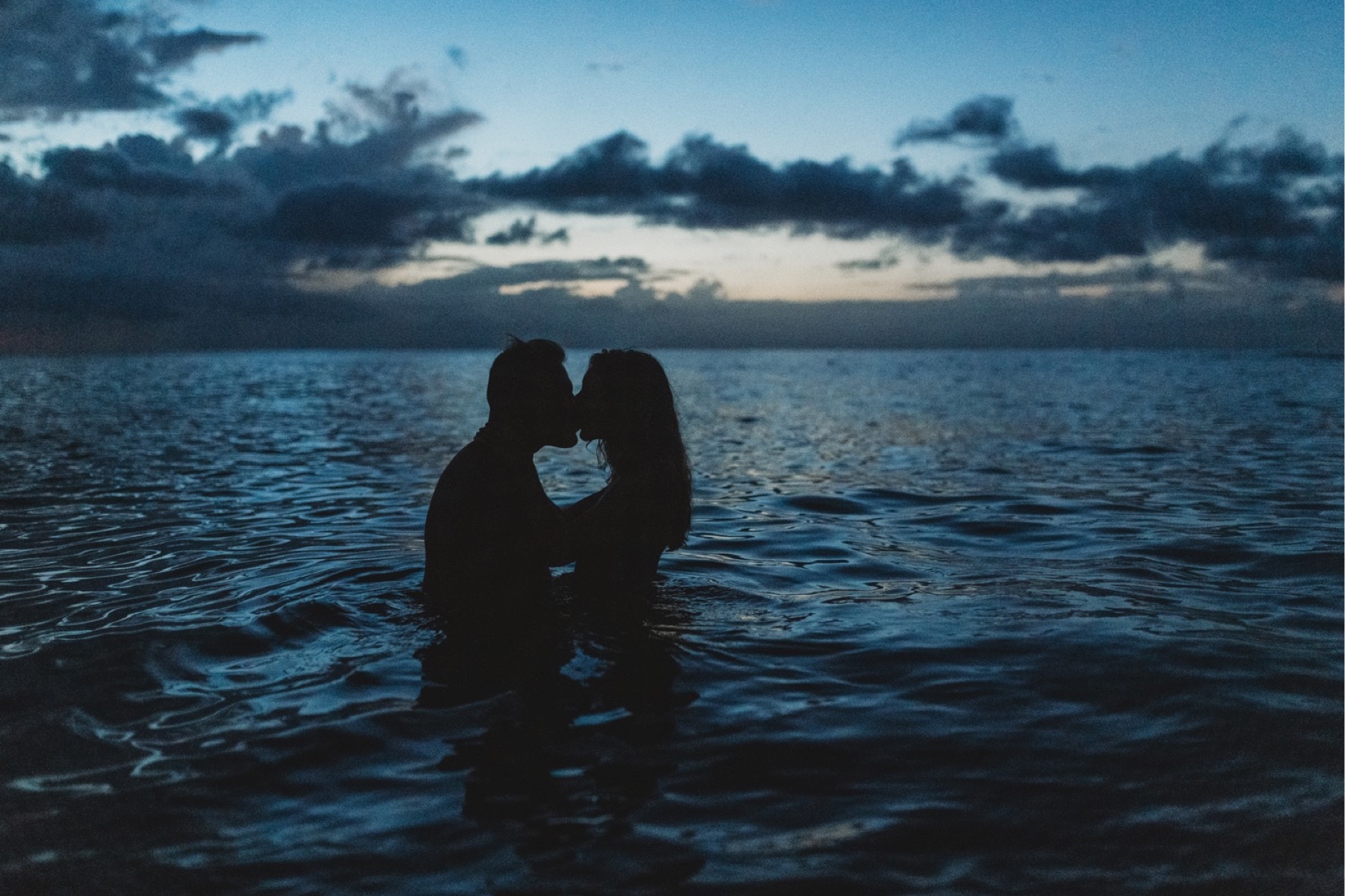 Couple kissing in the water after sunset