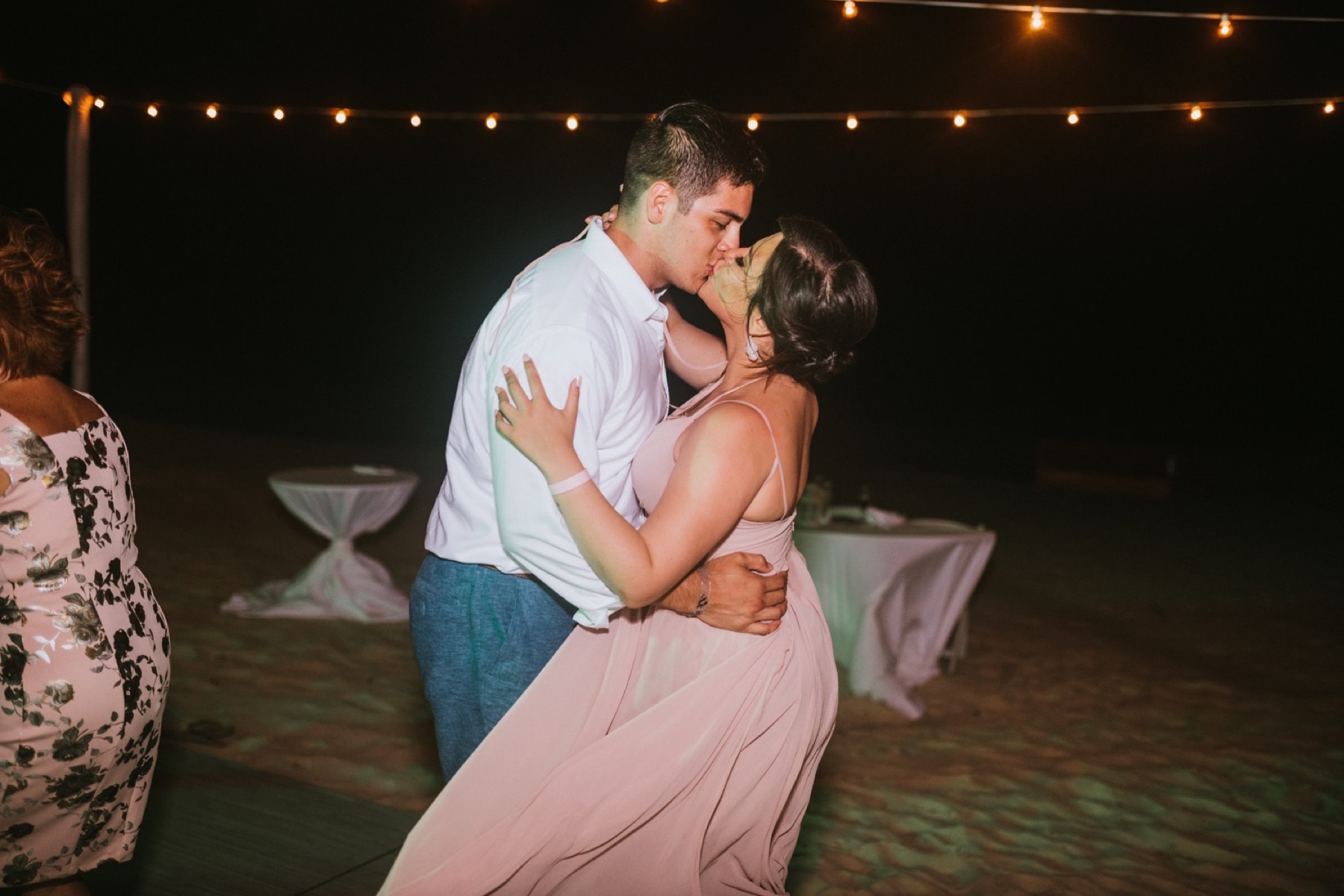 Maid of honor and husband kissing while dancing at wedding