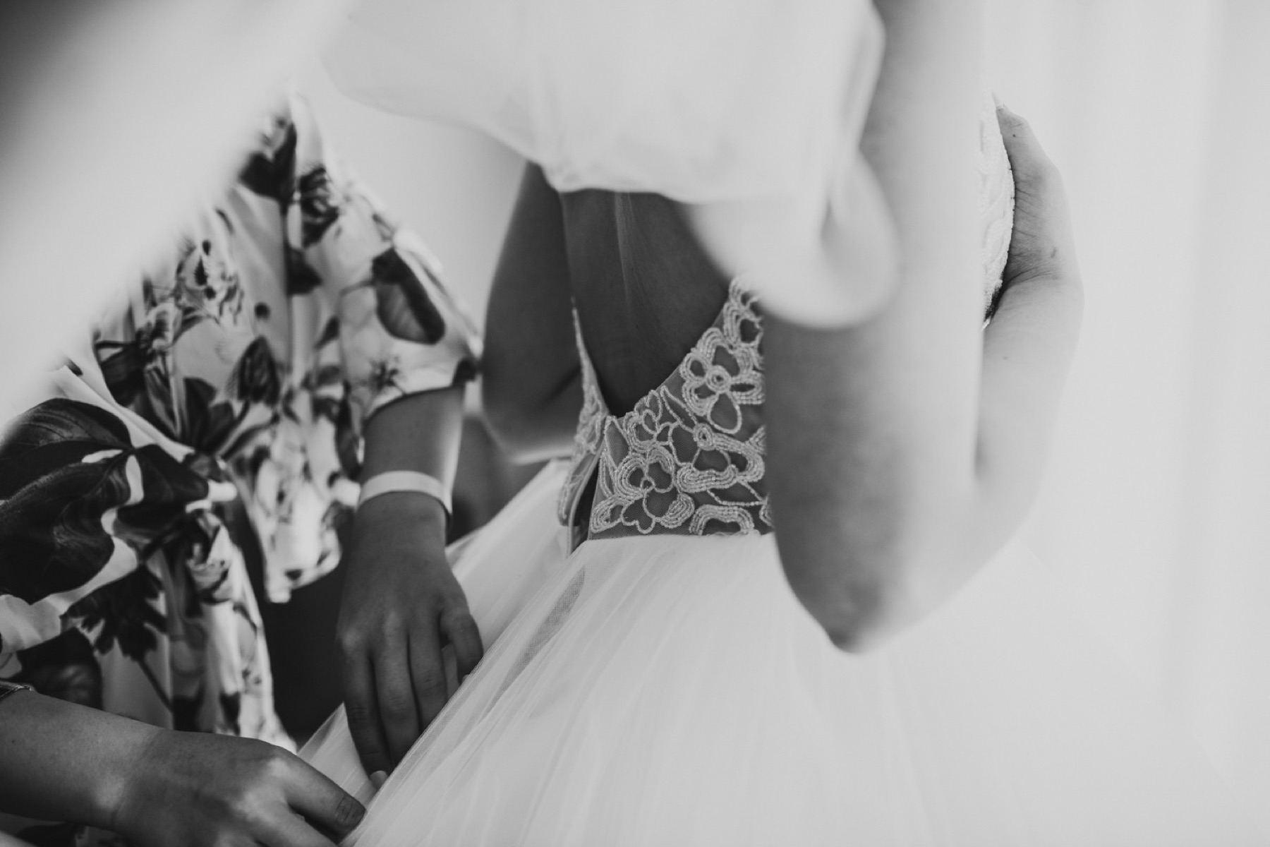 Black and white photo of the brides dress being zipped by her maid of honor