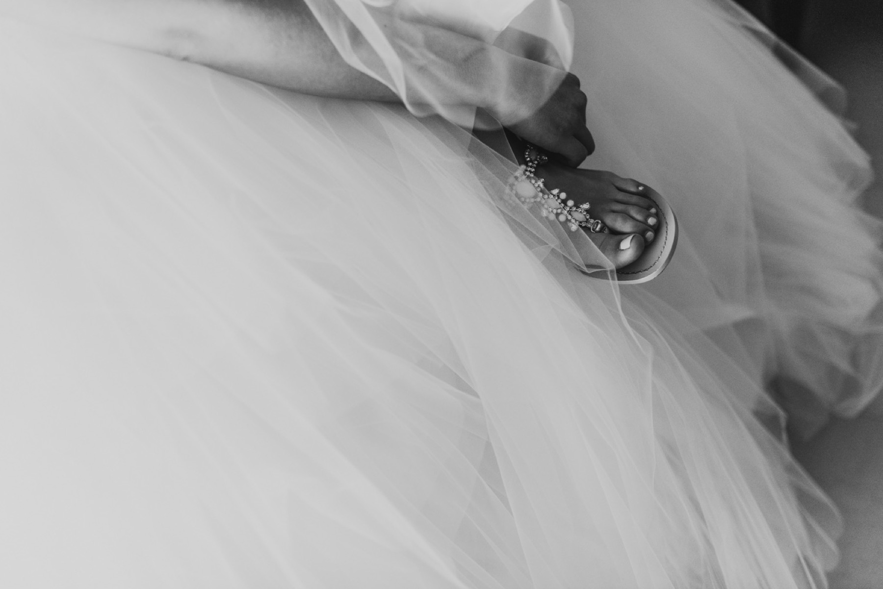 Black and white photo of bride putting on her wedding shoes