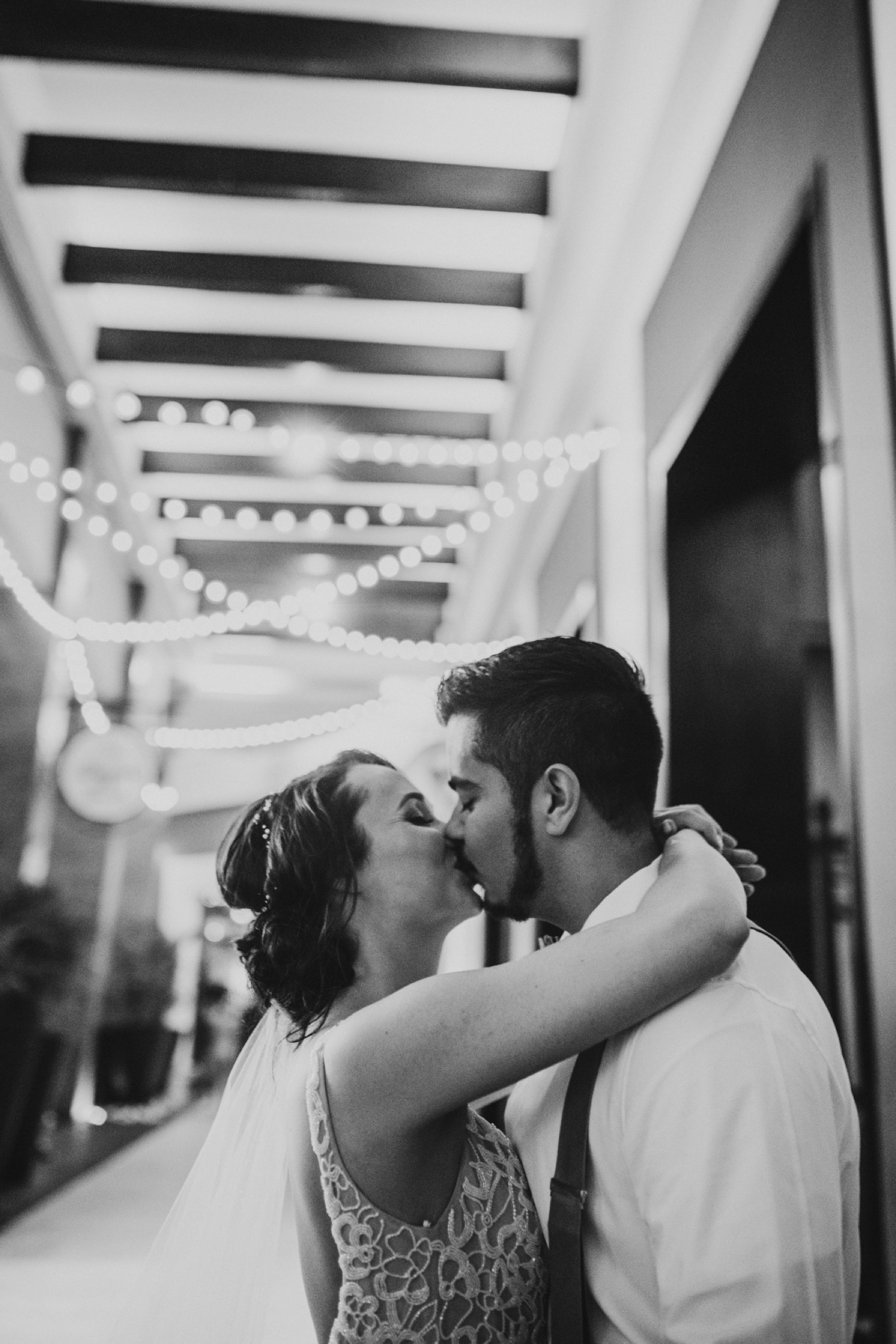 Black and white photo of bride and groom kissing in hallway of lights at Hard Rock Punta Cana