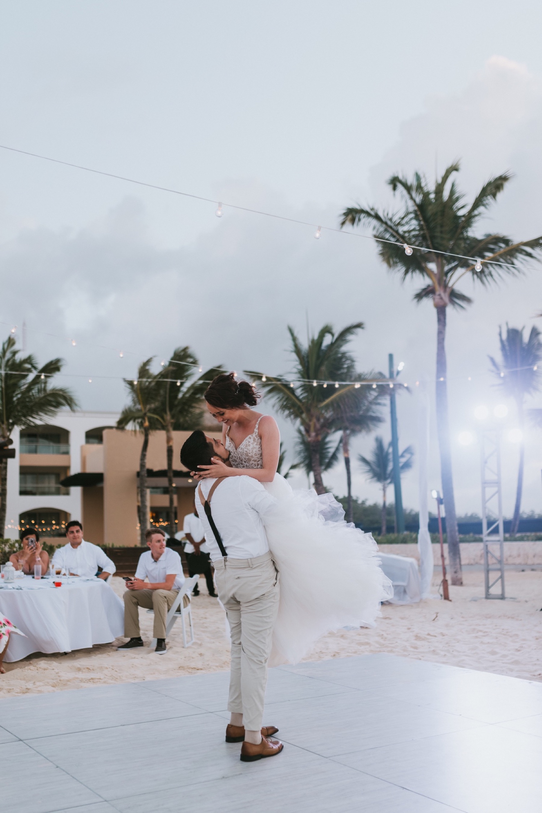 Groom picking bride up during first dance with dj lights in the background at hard rock punta cana
