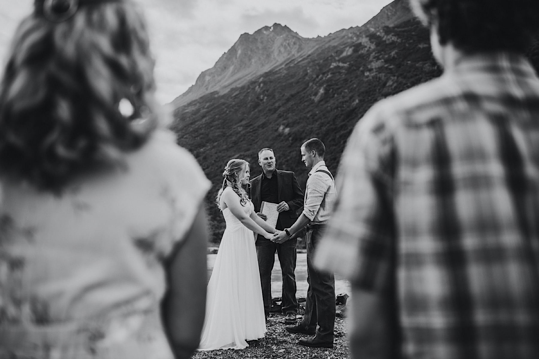 A black and white photo through guests at an intimate wedding by Knik Glacier