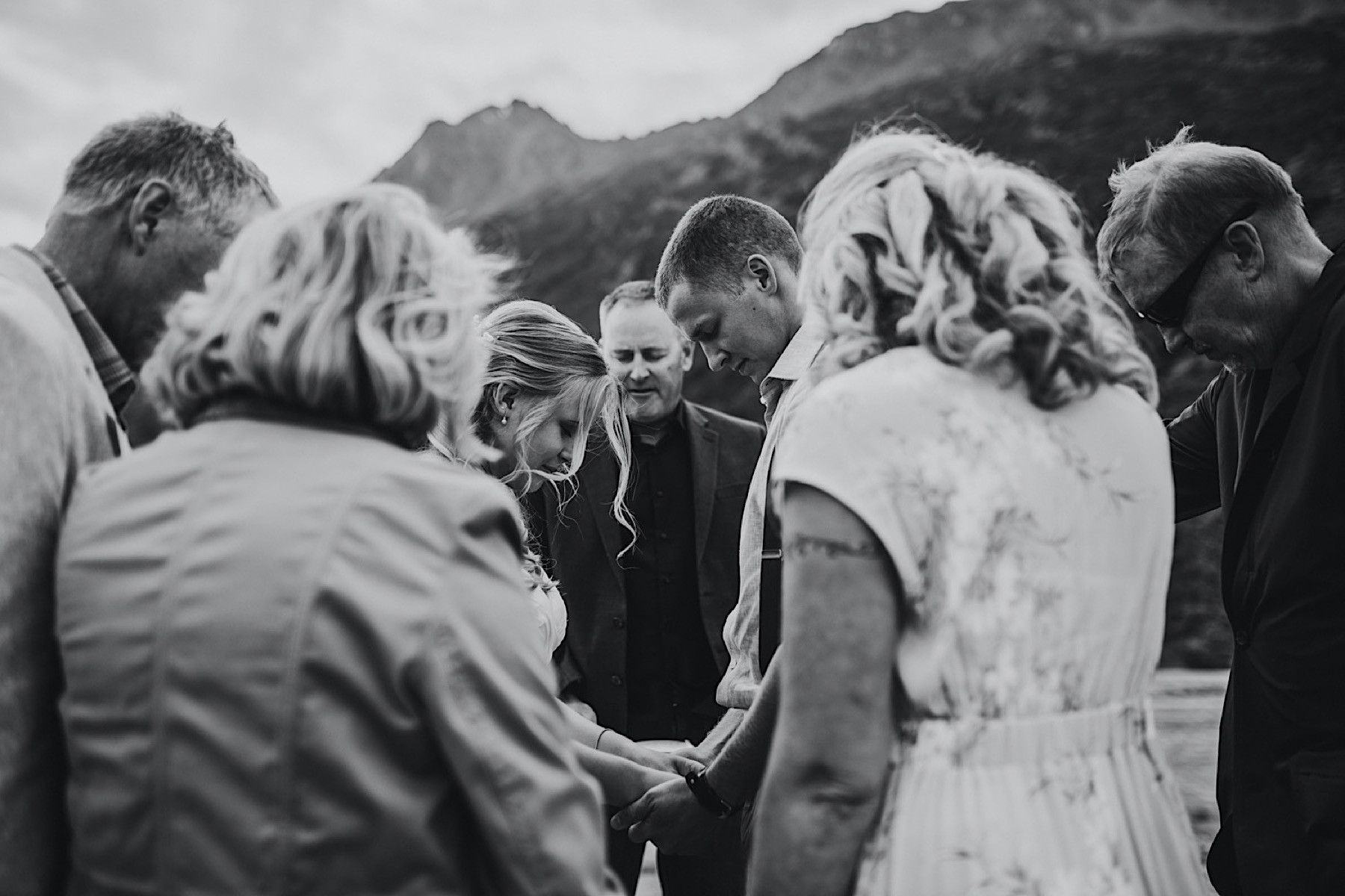 Black and white photo of family praying over bride and groom