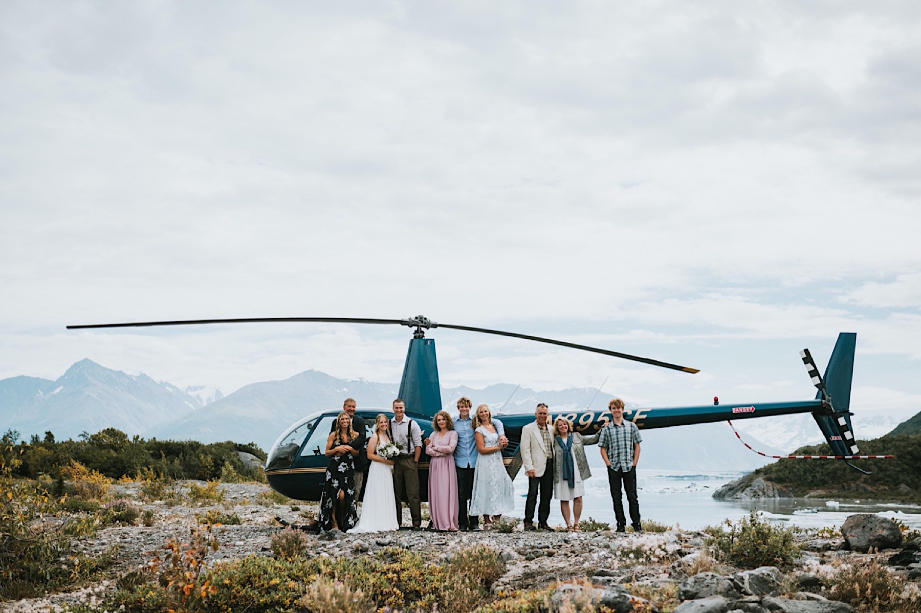 Photo of an entire wedding party standing in front of a helicopter
