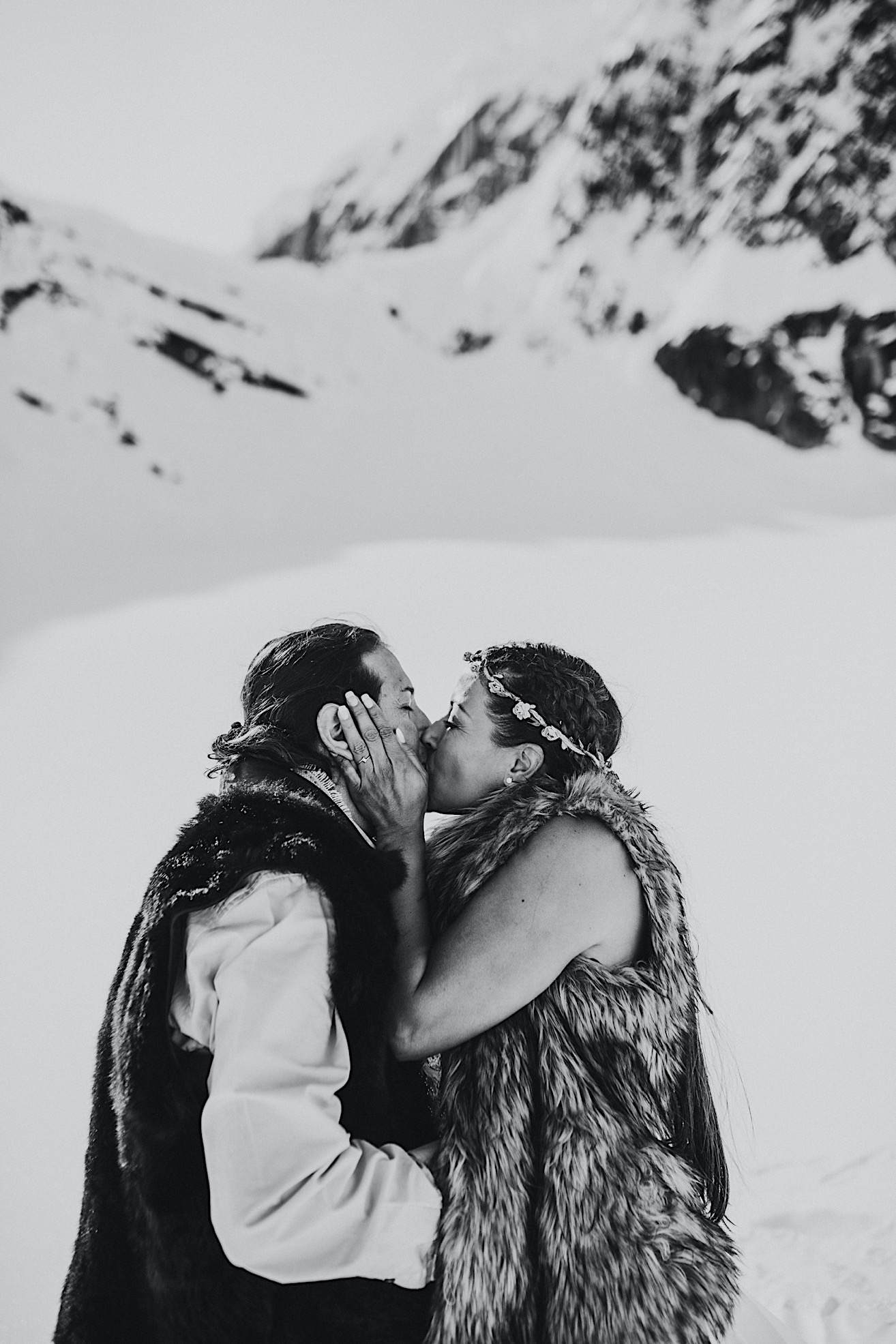 Black and white photo of couple kissing on a snow packed glacier