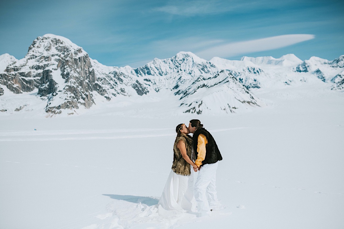Bride and groom kissing on a snow packed glacier after their glacier elopement