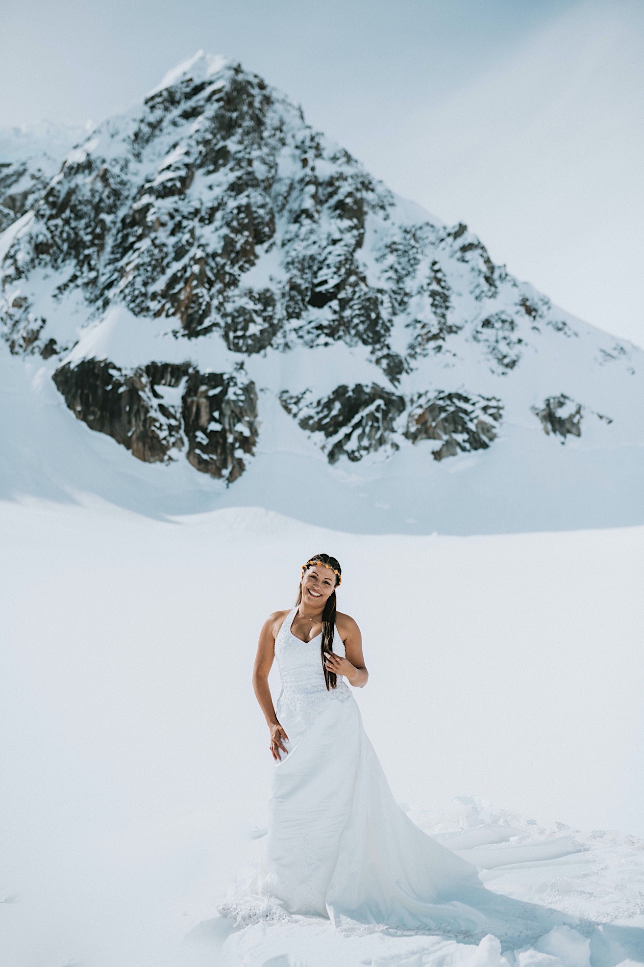 Bride standing in front of a mountain peak after her ceremony on a glacier